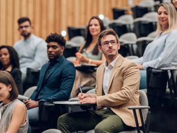 Diverse group attentively listening in a modern lecture hall.