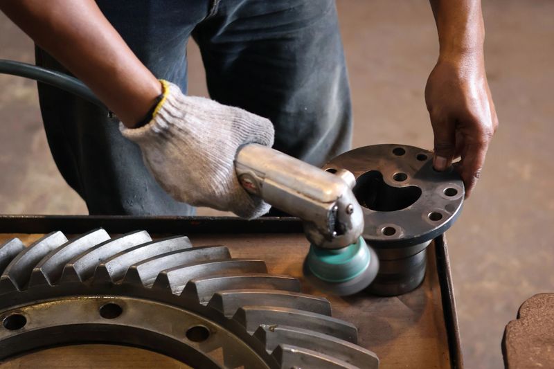 The builder works with an angle grinder. Wire cleaning brush. Cleaning metal embedded from rust and concrete. Worker using grinder to clean rust from metal.