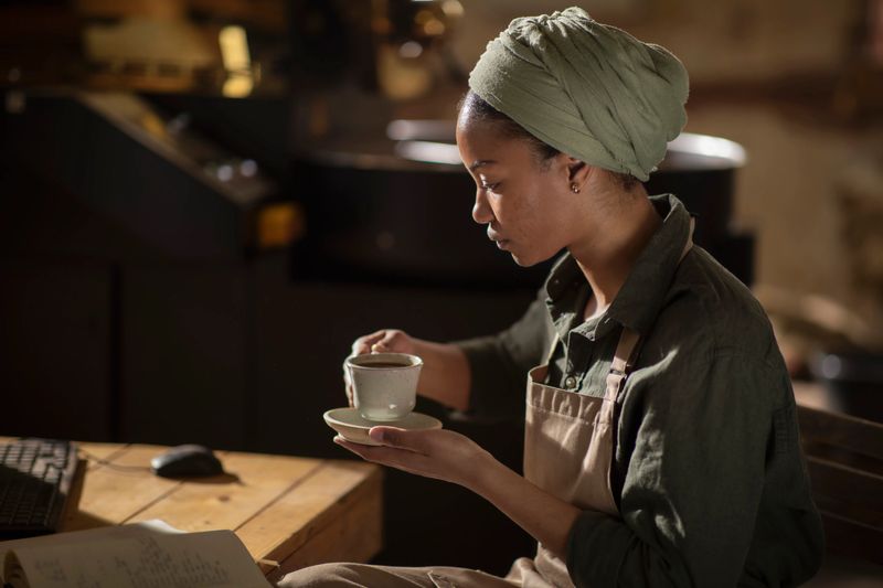 A calm moment of a woman savoring coffee, surrounded by inviting warmth and relaxed atmosphere; Ideal for themes of relaxation, contemplation, and the cafe experience
