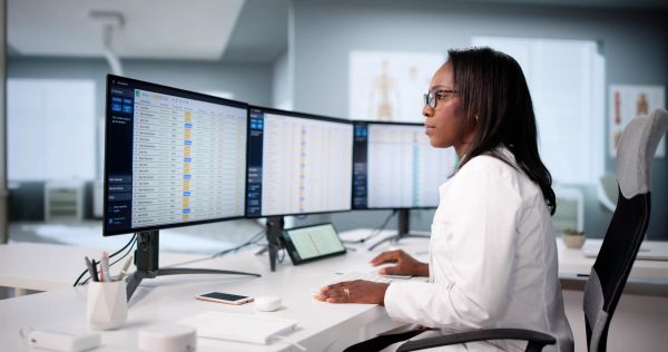Woman analyzing medical data on multiple monitors.