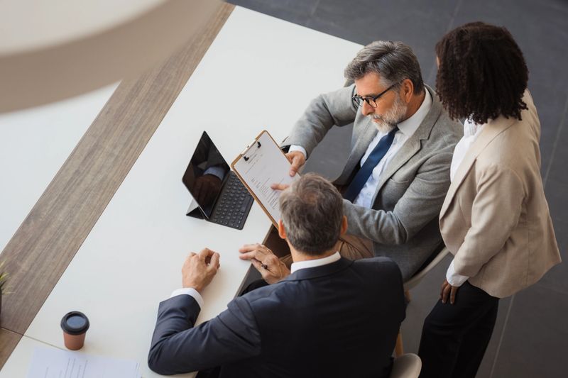Three business people discussing a document during a corporate meeting
