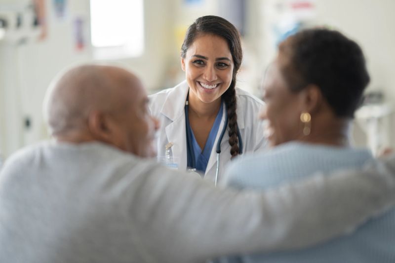 A compassionate Asian female doctor shares a warm smile with elderly patients in a modern hospital, highlighting care, trust, and teamwork in a clinical setting.