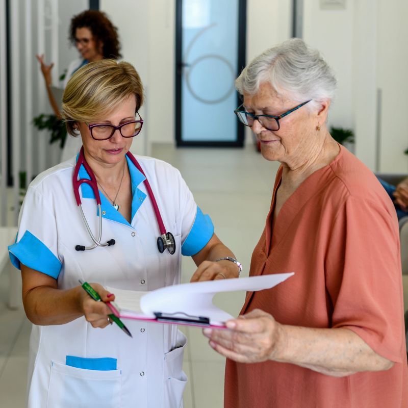 A female doctor is talking to a senior patient in the hospital lobby