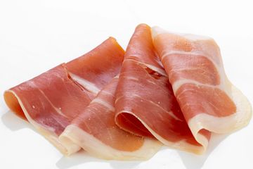 Three slices of prosciutto on a white background.