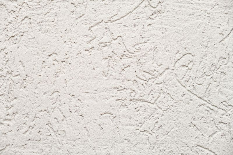 White stucco wall texture background with rough granular pattern. Detailed abstract surface for interior design, building material, or decorative plaster concept.