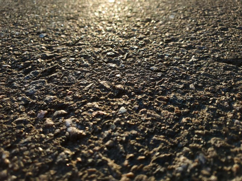 Close-up of an asphalt road, asphalt surface, road at sunset, sunbeam on asphalt, repair, restoration.