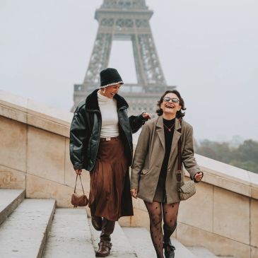 Two friends walking happily near the Eiffel Tower.