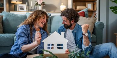 Happy couple celebrating with a house cutout.