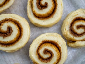 Unbaked cinnamon rolls on parchment paper.