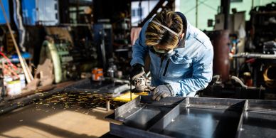 Worker grinding metal in a workshop.