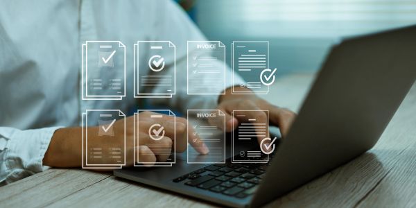 Person using laptop with invoice check icons.