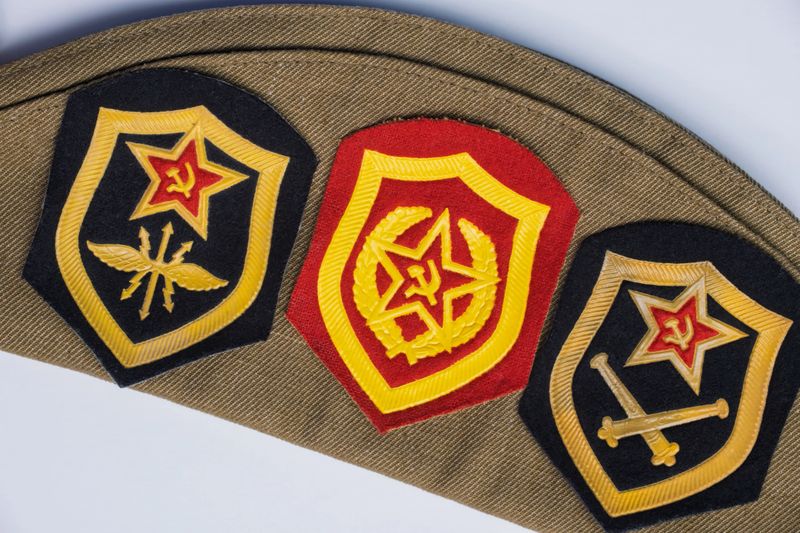 Russian Soviet military cap with service patches. Green cap and three patches all with ruby stars and hammer and sickle emblems. High quality photo