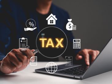 Person using laptop with tax-related icons floating around.