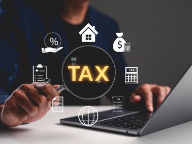 Person using laptop with tax-related icons and the word 'TAX' highlighted.