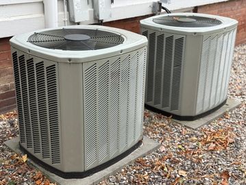 Two outdoor air conditioning units near a house.