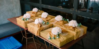 Gift boxes wrapped in gold paper with white floral decorations.