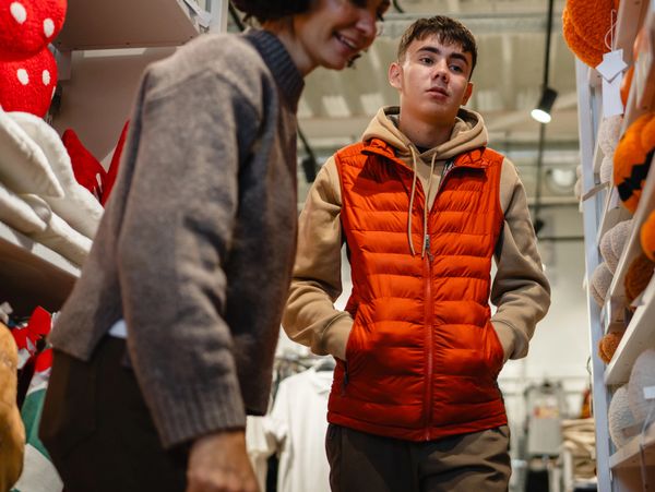 Young man in an orange vest shopping with a woman in a store aisle.