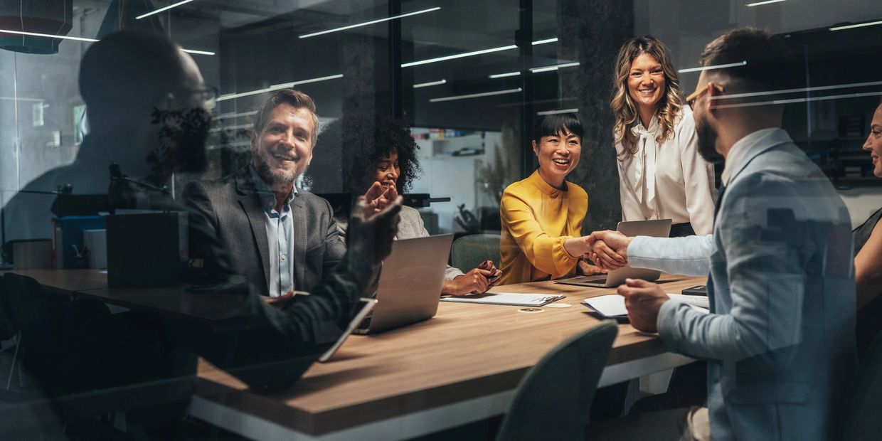 Business team shaking hands and smiling during a meeting in a modern office.
