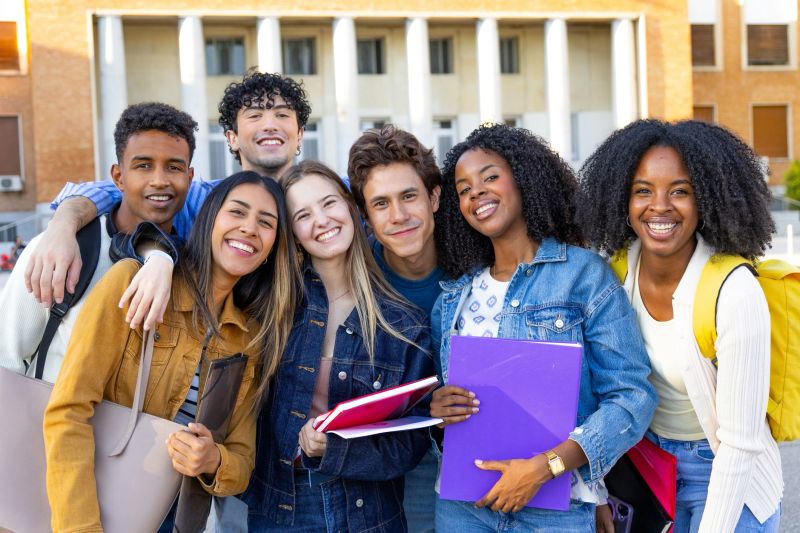 Group of happy young students standing together on university campus, embracing education and friendship