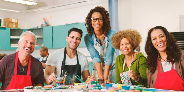 A diverse group happily painting together in an art class.