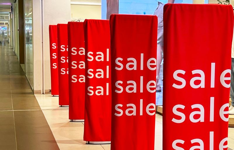 Red banners displaying the word sale are prominently displayed in a modern shopping mall. They line the walkway, enticing customers to explore the store offerings.