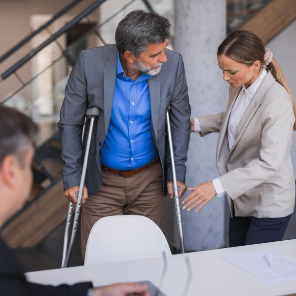 picture of woman helping a man in crutches 