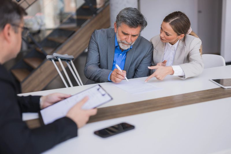 Couple signing an insurance claim form with a financial advisor after an injury