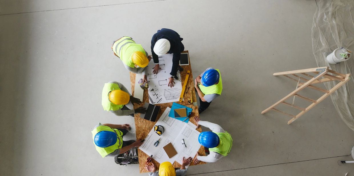 Construction team reviewing blueprints around a table.