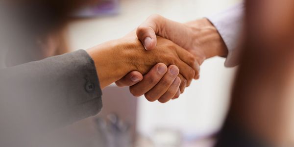 Two people shaking hands in a professional setting.
