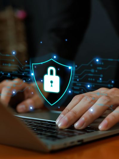Hands typing on a laptop with a digital lock shield overlay.