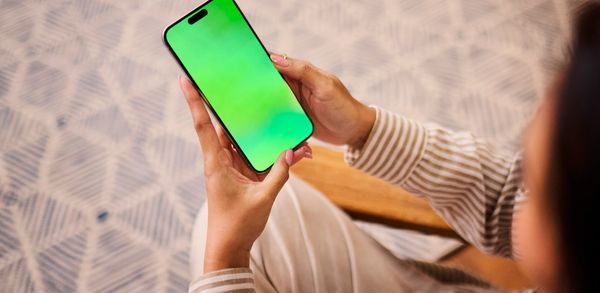 Person holding smartphone with green screen.