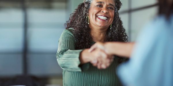 Smiling woman shaking hands with someone.