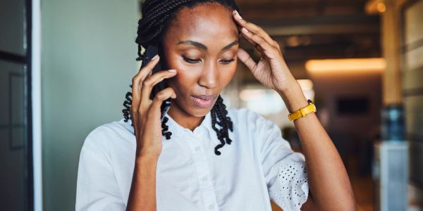 Worried woman talking on phone indoors.