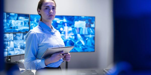 Une femme avec une tablette dans une salle de surveillance.
