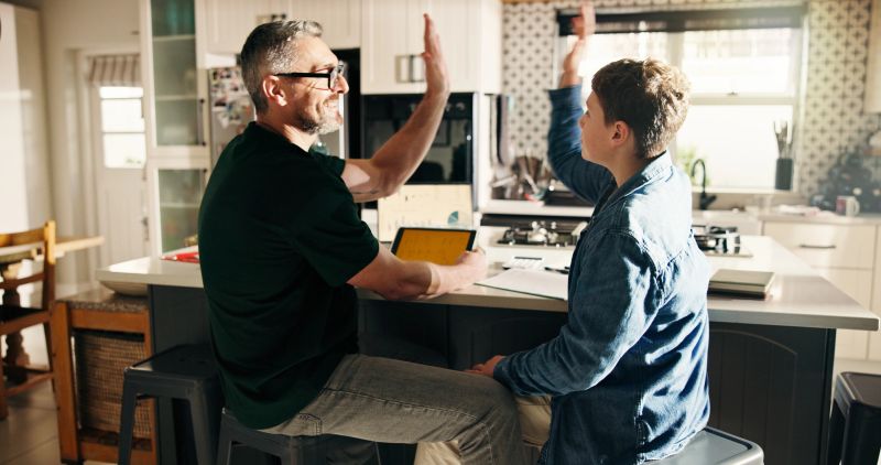 Father, kid and high five in home for elearning success, smile and well done with family in kitchen. Dad, child and hands together in homeschool for achievement, education or celebration with tablet