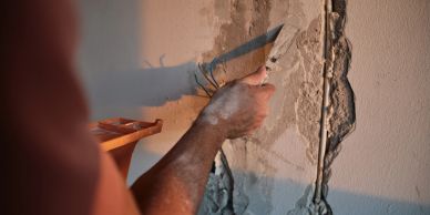 Person repairing a damaged wall with plaster.