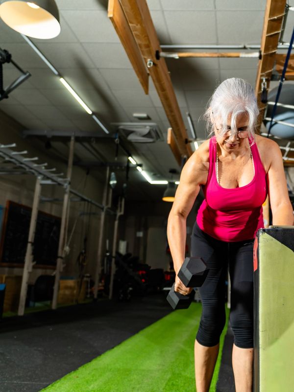 Older woman lifting dumbbell in gym.