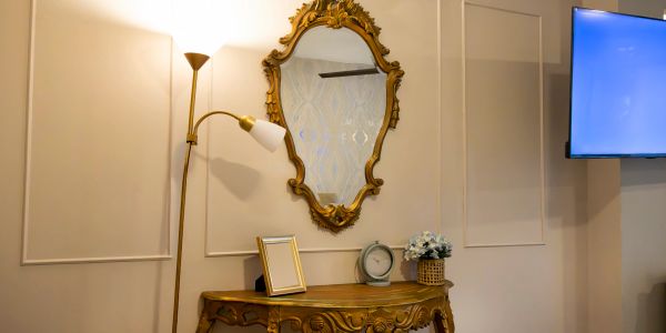 Ornate mirror and wooden console table with lamp and TV.