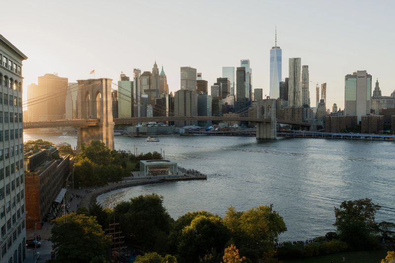 Brooklyn bridge and manhattan skyline at golden hour over the east river, dumbo waterfront park and soaring skyscrapers lit warmly