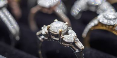 Close-up of a diamond ring with other rings blurred in the background.