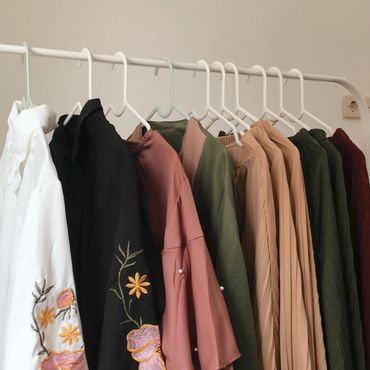 A row of various colored clothes hanging neatly on white hangers.