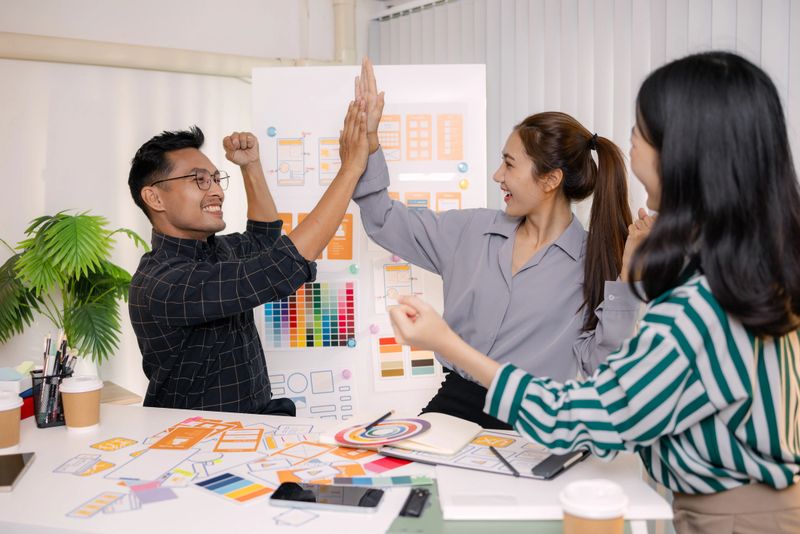 UX/UI designers collaborating during a creative workshop to test interface ideas and exchange feedback for app development, emphasizing teamwork and innovative design thinking.
