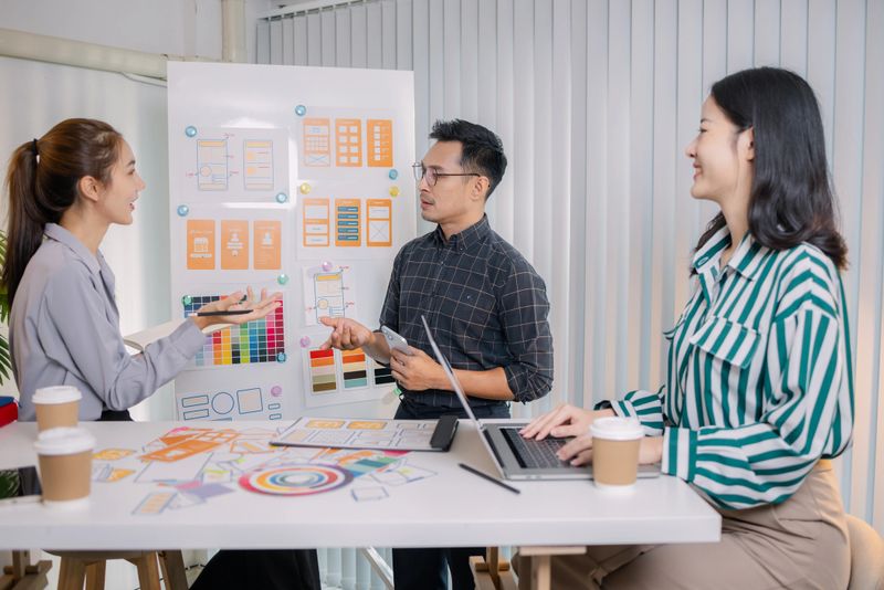 UX/UI designers collaborating during a creative workshop to test interface ideas and exchange feedback for app development, emphasizing teamwork and innovative design thinking.