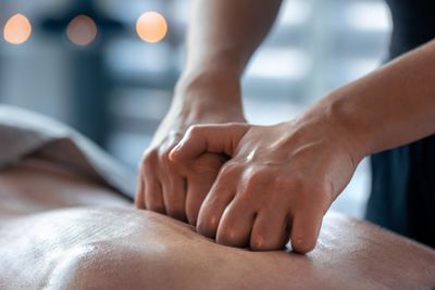 Hands giving a deep tissue massage on a back.
