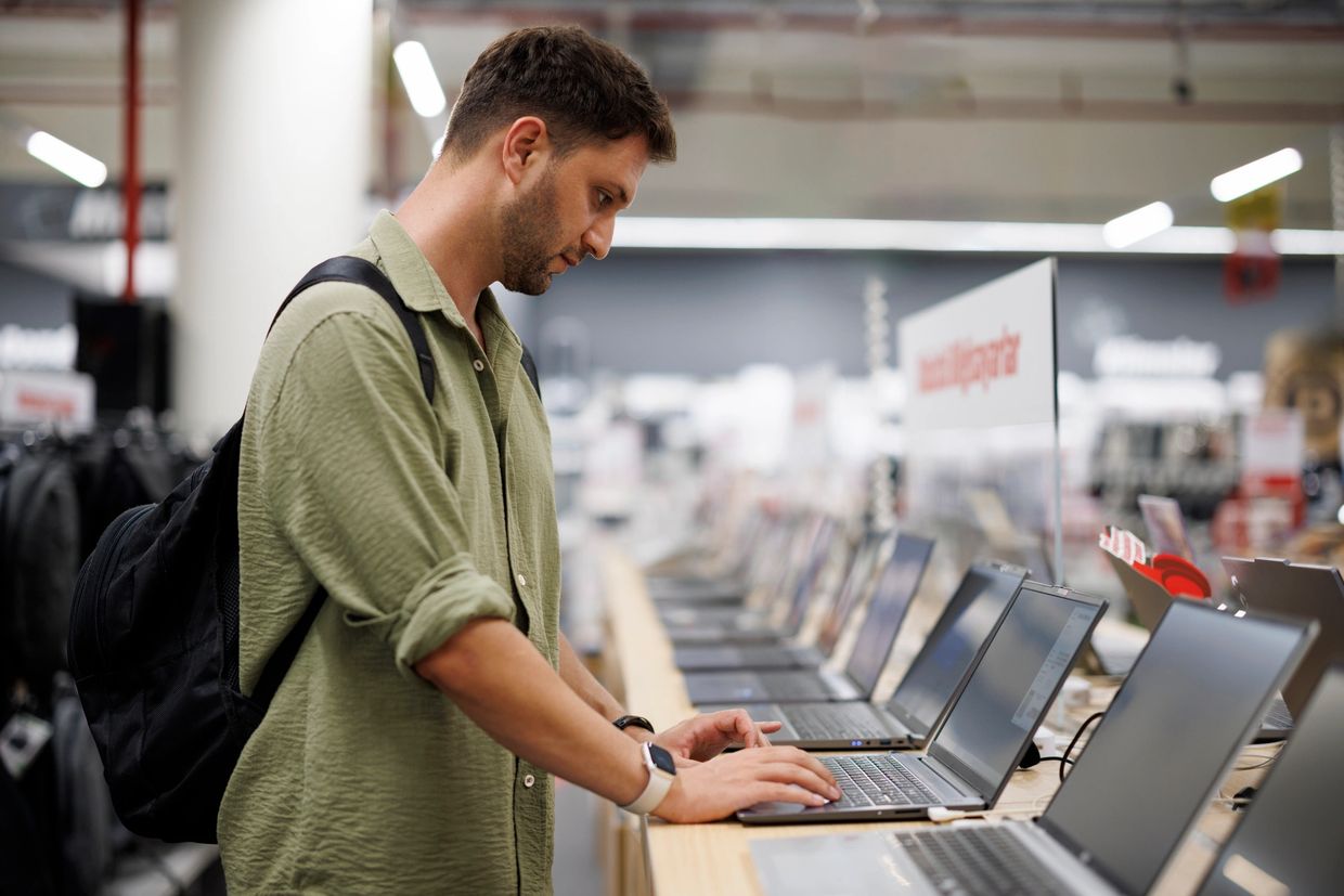 A man testing laptops in an electronics store.
