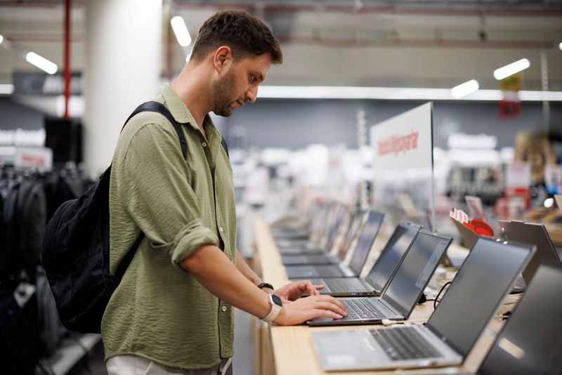 Modern male customer choosing laptop in retail computer store