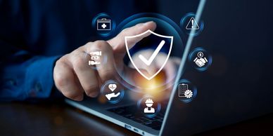 Finger interacting with digital shield and security icons on laptop.