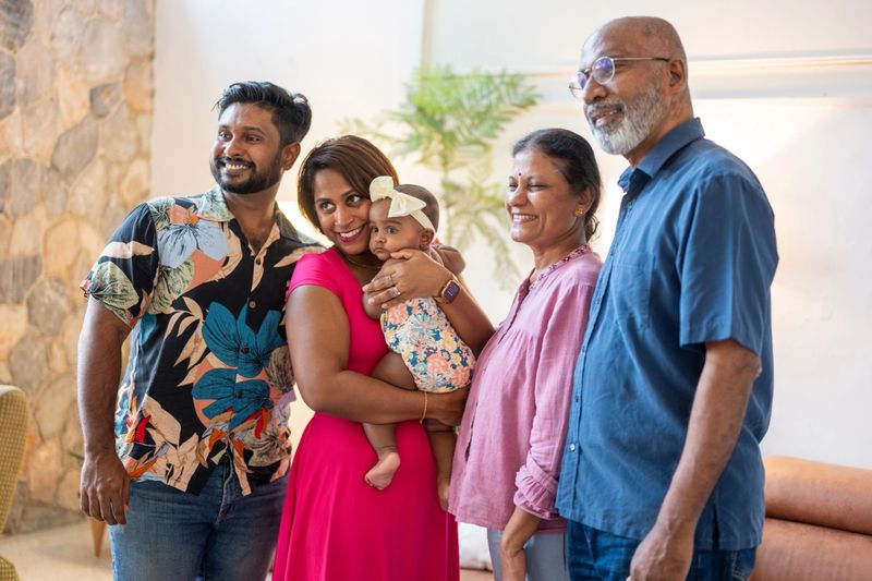 Portrait of an Asian Indian family bonding together in the living room, looking away