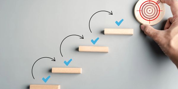 Wooden blocks with checkmarks and a target symbolizing goal achievement.