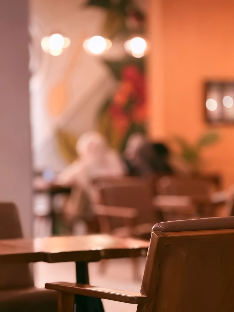 Cozy cafe interior with warm lighting and blurred background, showing people enjoying a relaxed atmosphere. Suitable for lifestyle, hospitality, or interior design themes.